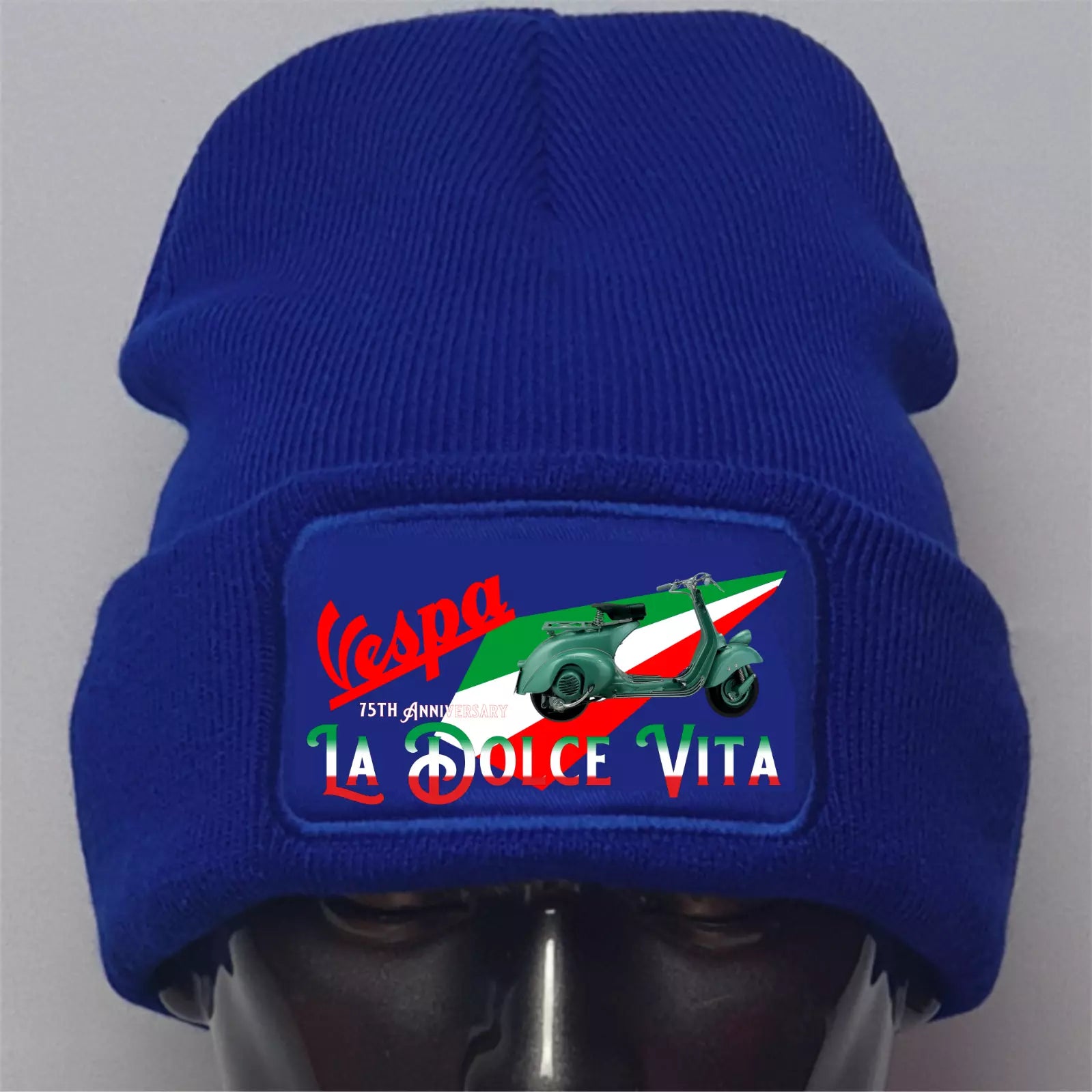 Blue beanie with Vespa logo and 'La Dolce Vita' text on a gray background