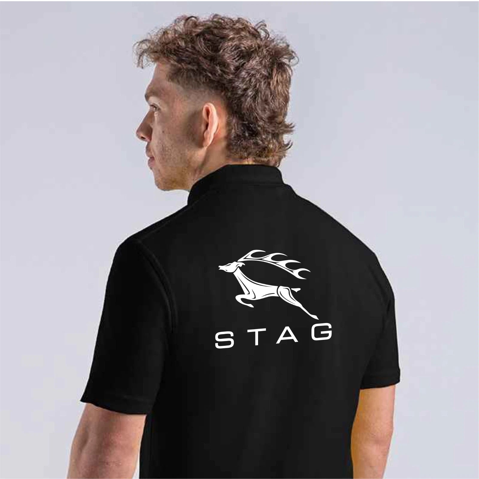 Man wearing a black polo shirt with 'STAG' logo on the back against a light gray background
