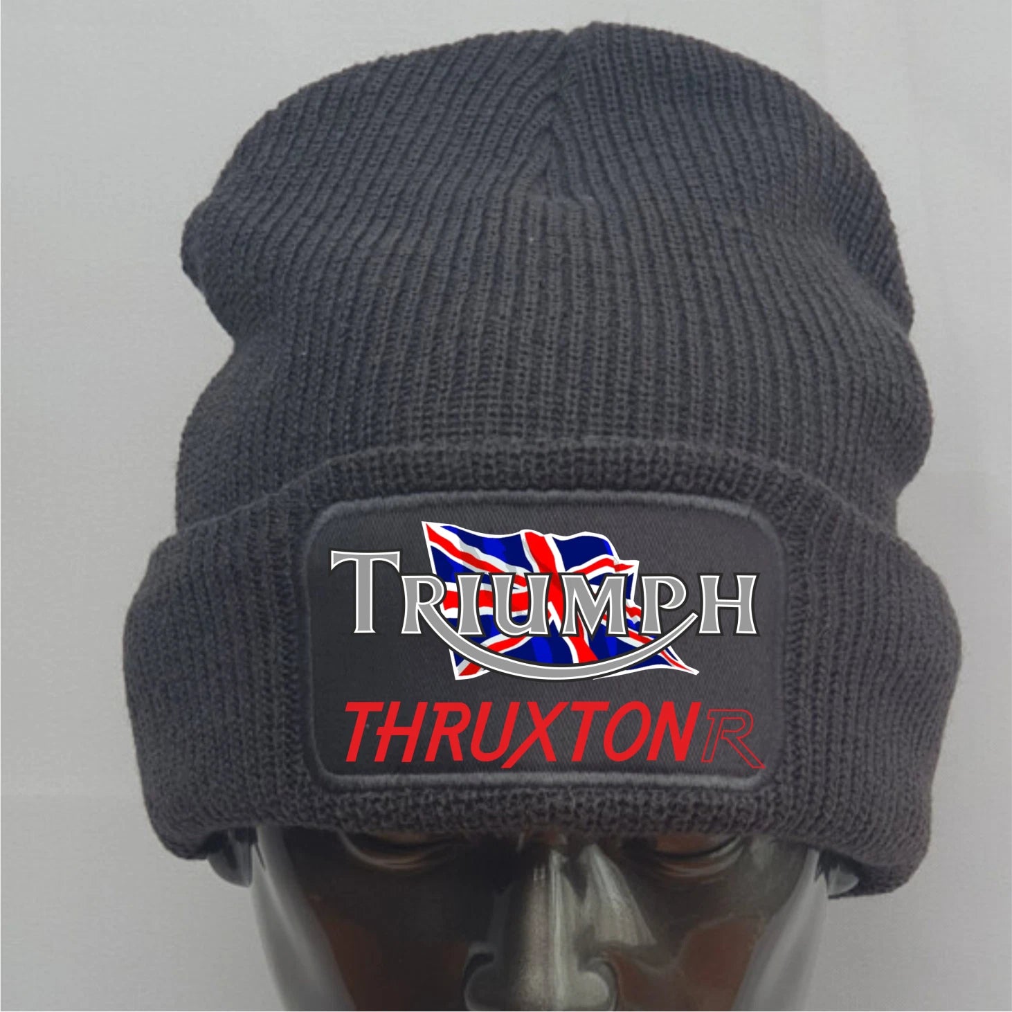 Dark gray knit beanie with Triumph Thruxton logo on a mannequin head against a light gray background