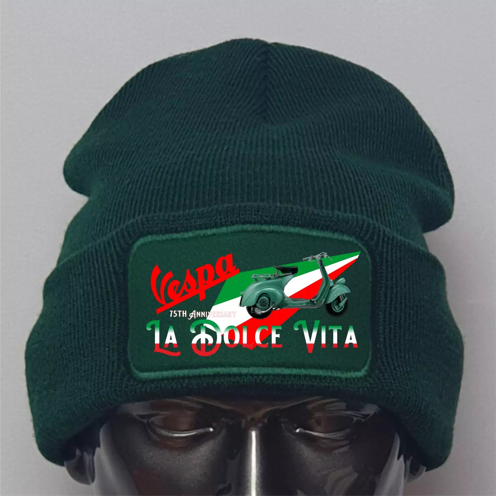 Green beanie with Vespa La Dolce Vita patch on a mannequin head against a gray background
