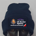Navy beanie with UK Border Agency logo on a gray background