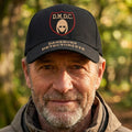 A black baseball cap featuring a front shield patch with the text 'D.M.D.C.' referring to the BBC comedy series The Detectorsts.