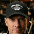 A black baseball cap with a white printed graphic on the front reading 'ROYAL ENFIELD BULLET 500' with winged badge details, shown on a plain white background.