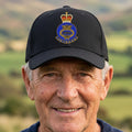 A black baseball cap featuring a detailed printed British Merchant Navy Veteran crest on the front, set against a plain white background.