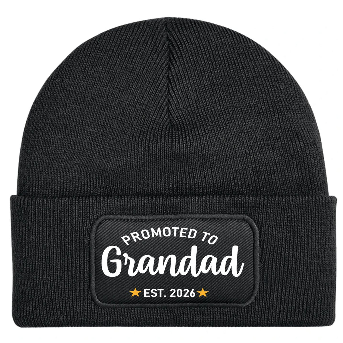 A black ribbed knit beanie hat with a folded cuff, featuring a rectangular black patch on the front with the white text 'PROMOTED TO Grandad' and 'EST. 2026' with small gold stars.