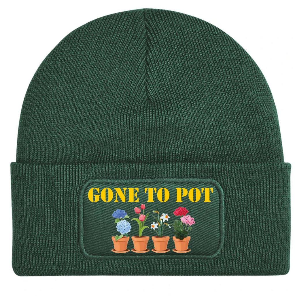 A dark green ribbed knit beanie hat with a folded cuff, featuring a rectangular printed patch on the front that reads 'GONE TO POT' in yellow above four small potted flowers in blue, pink, red, and white.