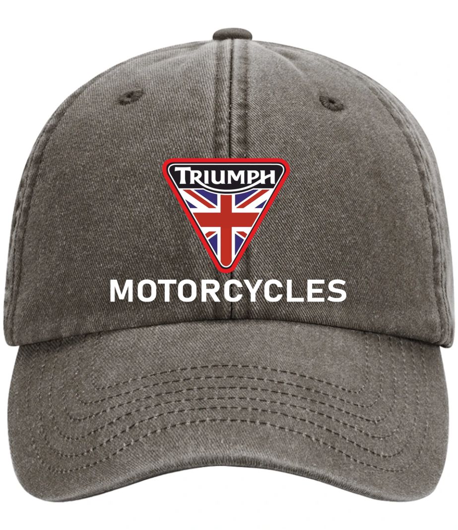 A washed dark gray baseball cap featuring a red, white, and blue triangular embroidered patch with the word 'Triumph' and a Union Jack flag, with 'MOTORCYCLES' embroidered in white below it.