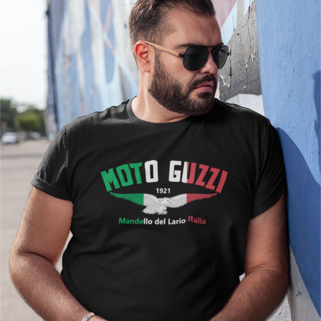 Man wearing a black t-shirt with Moto Guzzi logo against a colorful wall.