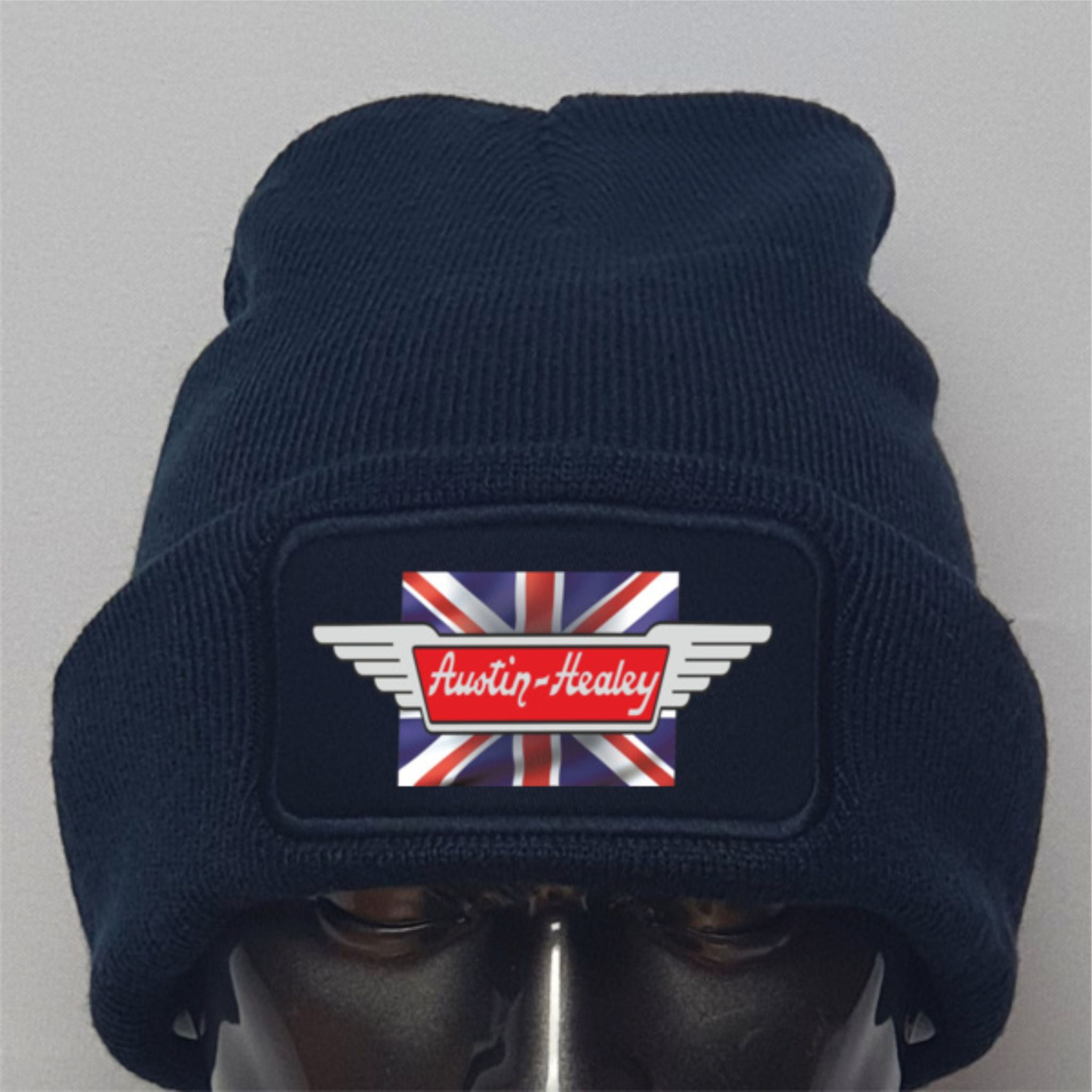 Navy blue beanie with Austin-Healey logo featuring a Union Jack design on a gray background
