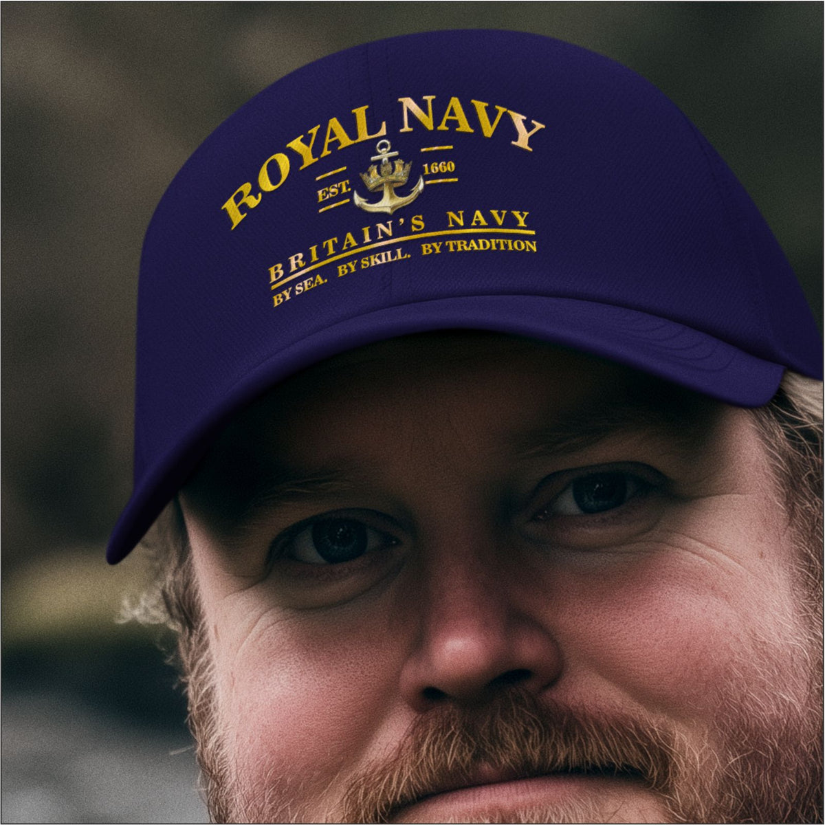 A close-up of a man wearing a dark navy blue baseball cap with yellow printed text reading 'ROYAL NAVY' and 'BRITAIN'S NAVY' with a small anchor emblem.