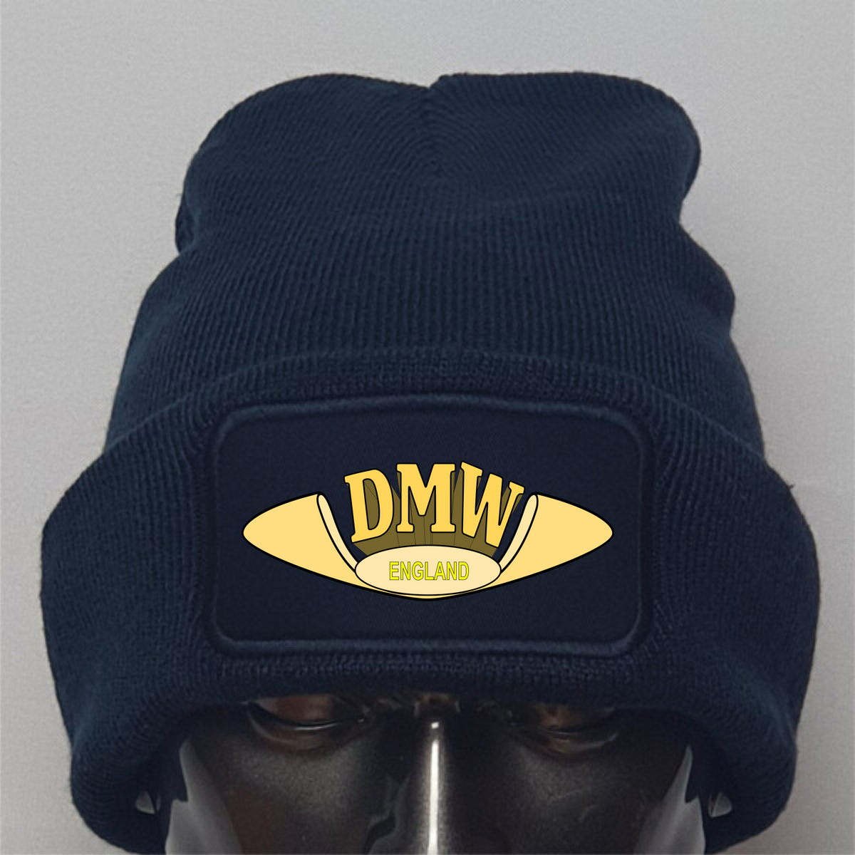 Navy blue beanie with a gold 'DMW England' logo on a gray background
