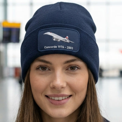 A navy blue ribbed knit beanie with a folded cuff, featuring an embroidered patch on the front that displays a Concorde jet and the text 'Concorde 1976 - 2003'.