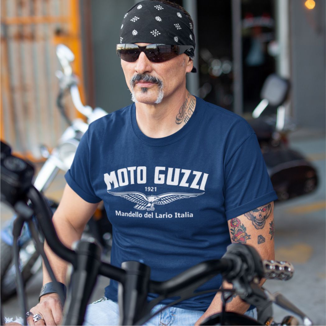 Man wearing a blue 'Moto Guzzi' t-shirt sitting on a motorcycle.