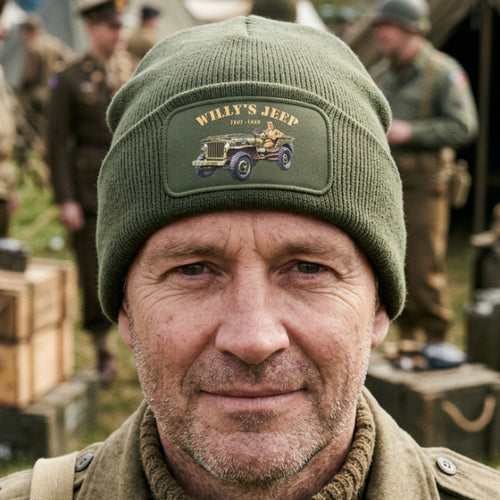 An olive green ribbed knit beanie hat with a folded cuff, featuring a rectangular printed patch on the front that reads 'WILLY'S JEEP 1911-1942' and shows a vintage jeep illustration.