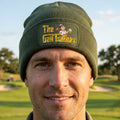 An olive green knit beanie hat featuring a rectangular color-printed patch on the front cuff with the text 'The Golf Father' and a cartoon golf character holding a beer mug.