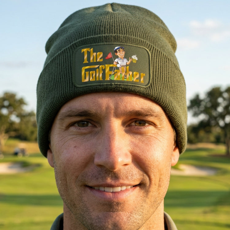 An olive green knit beanie hat featuring a rectangular color-printed patch on the front cuff with the text 'The Golf Father' and a cartoon golf character holding a beer mug.