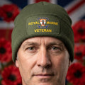 An olive green ribbed knit beanie with a folded cuff, featuring a rectangular Printed patch on the front that reads 'ROYAL MARINE VETERAN' with a Marine Corps emblem in the center.