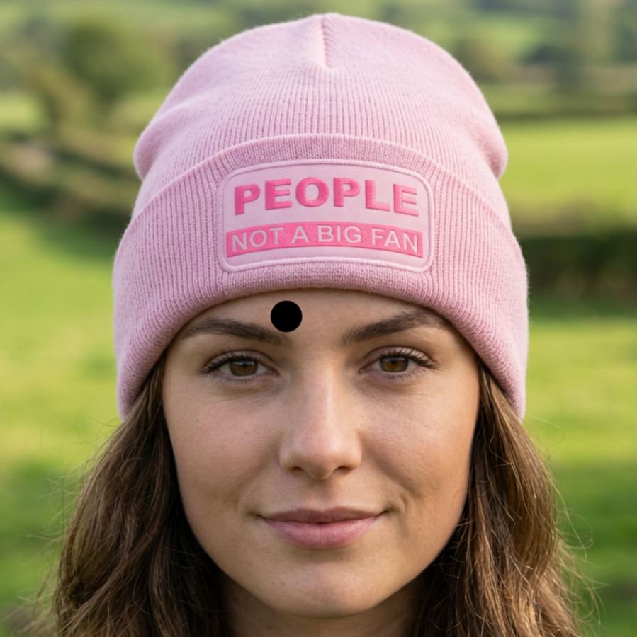 A pink ribbed knit beanie hat with a folded cuff, featuring a rectangular patch on the front that reads 'PEOPLE NOT A BIG FAN' in pink and white text.