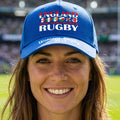 A royal blue baseball cap featuring 'ENGLAND WOMEN'S RUGBY 2027' printed on the front and brim. The front text is styled with the colors and flags of the Rugby Union, and the brim features 'Womans Rugby 2027' in white script.