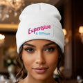 A white ribbed knit beanie hat featuring a white rectangular patch on the front cuff with the text 'Expensive & Difficult' in pink and blue lettering, set against a plain white background.