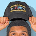 Person wearing a black cap with a humorous text and graphic design on a light blue background