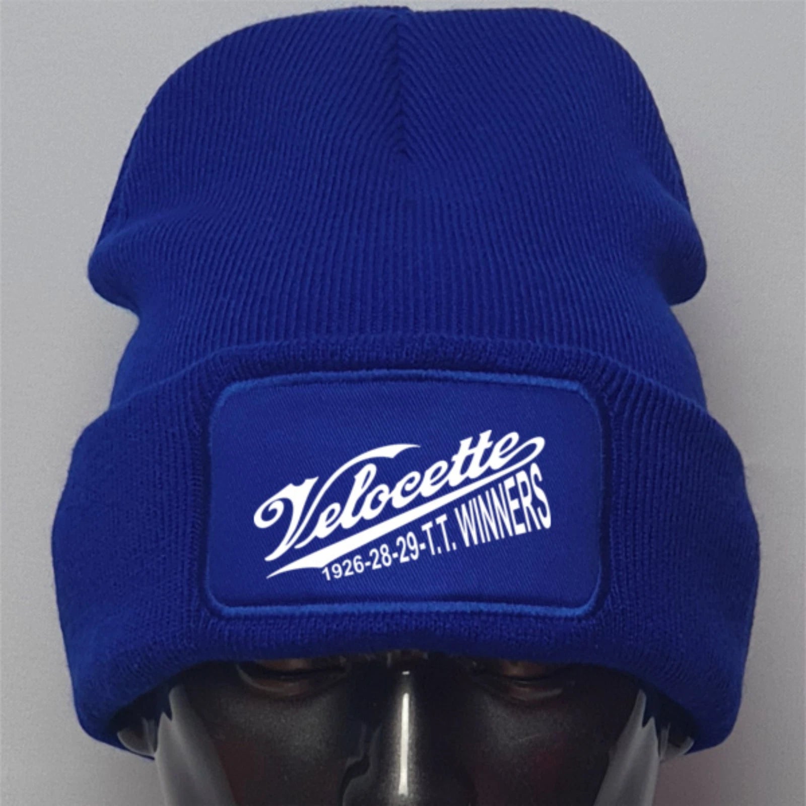 Blue beanie with Velocette logo on a gray background