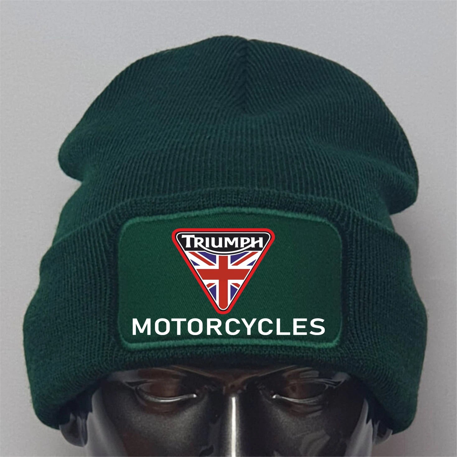 Green beanie with Triumph Motorcycles logo on a mannequin head against a gray background