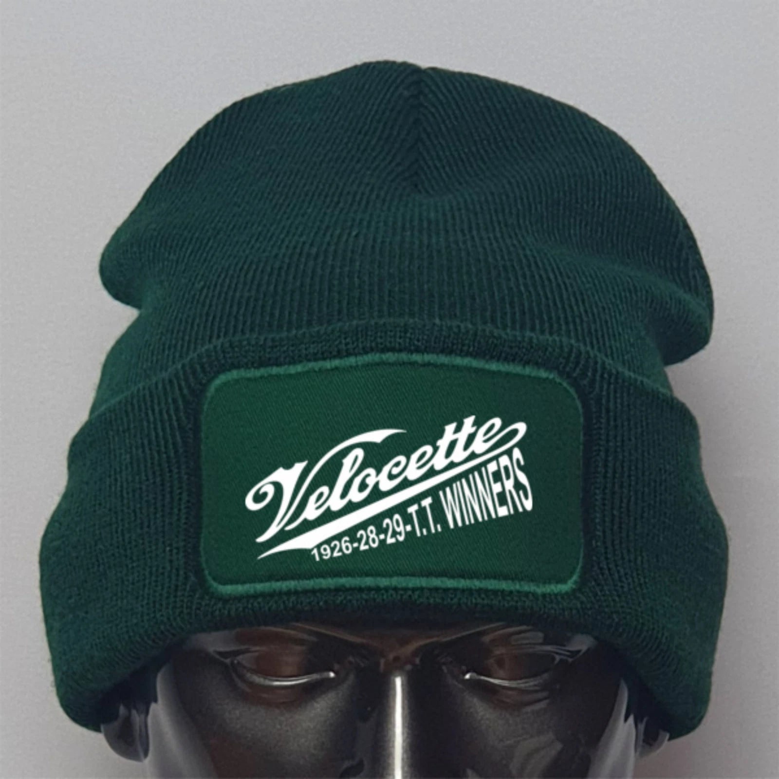 Green beanie with Velocette logo on a gray background