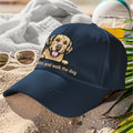 Navy blue cap with a dog illustration and text on a sandy background
