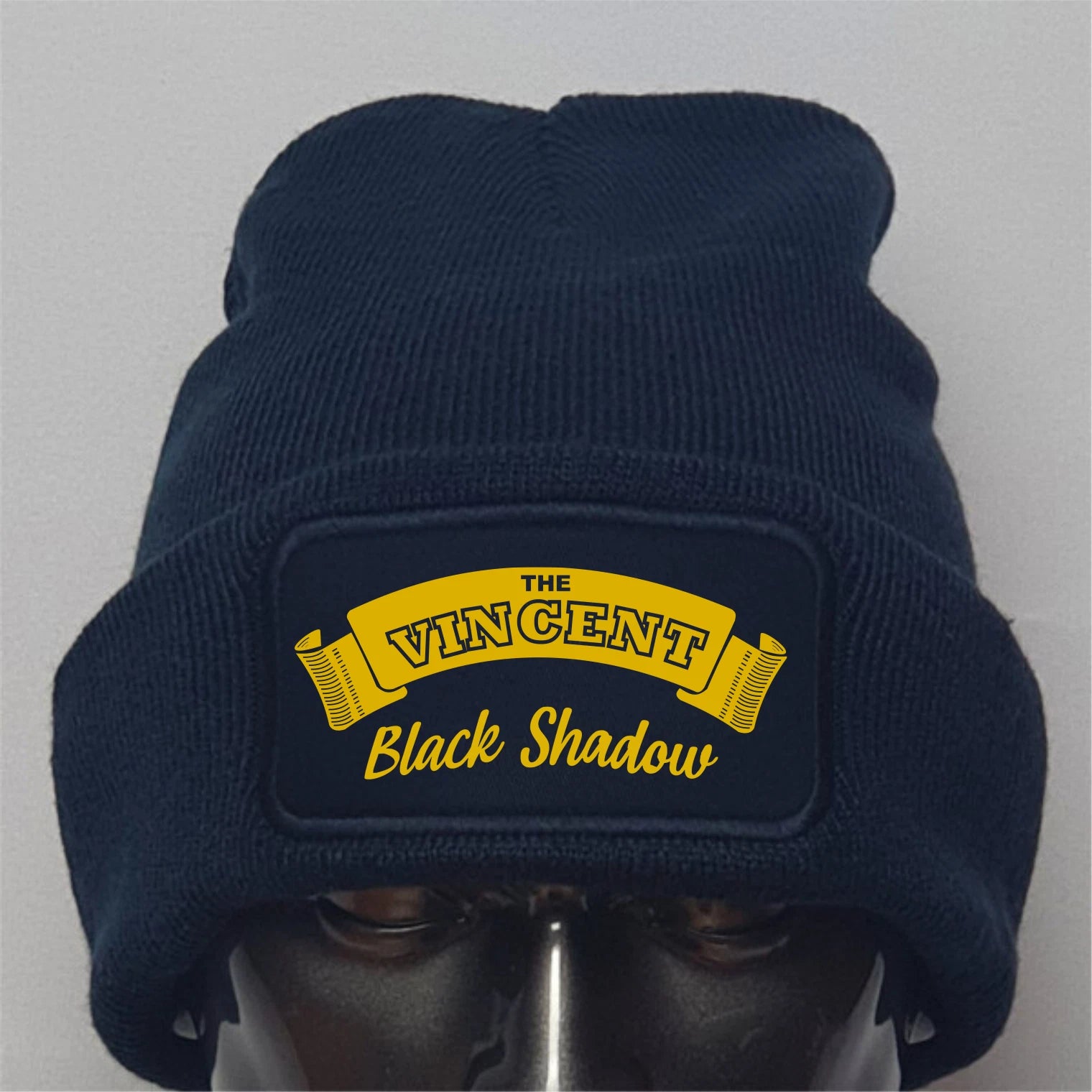 Navy blue beanie with yellow 'The Vincent Black Shadow' logo on a gray background