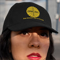Person wearing a black cap with a yellow Pan Am logo.