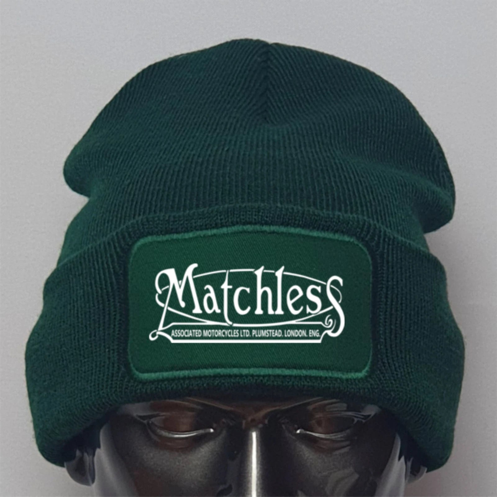 Green beanie with 'Matchless' logo on a mannequin head against a gray background
