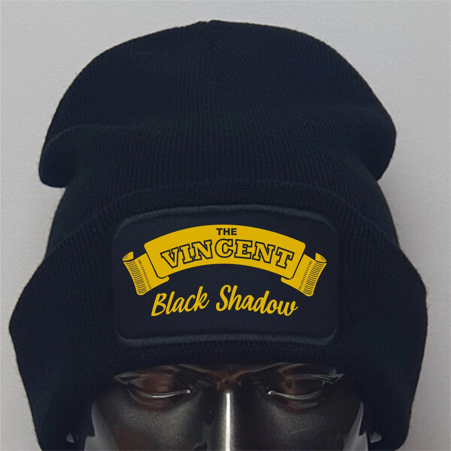 Black beanie with yellow text on a gray background
