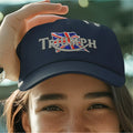 Person wearing a navy blue cap with 'Triumph' logo, blurred green background