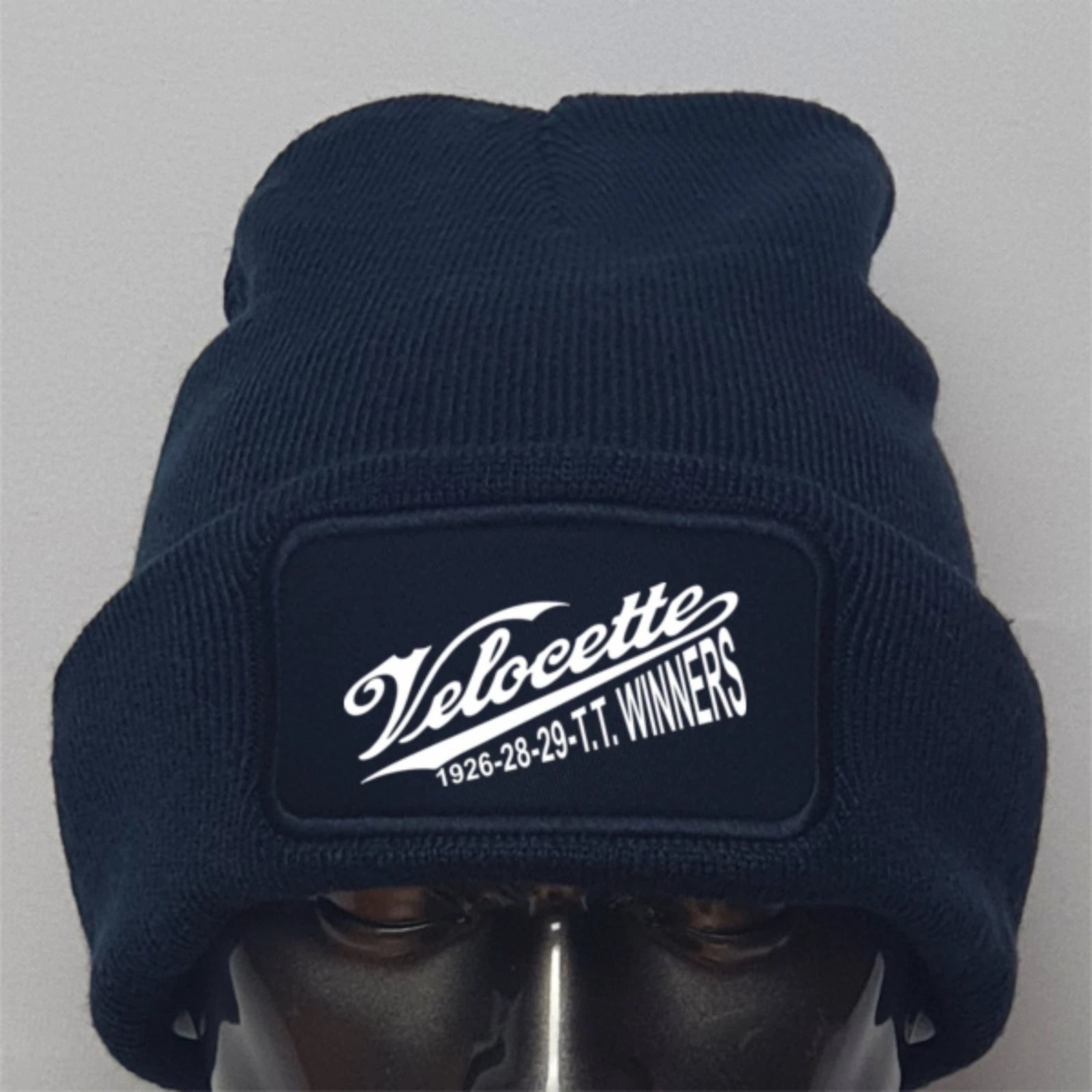 Navy blue beanie with Velocette logo on a gray background
