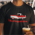 Person wearing a black t-shirt with a red and white car graphic and 'Metropolitan' text, holding a beer.