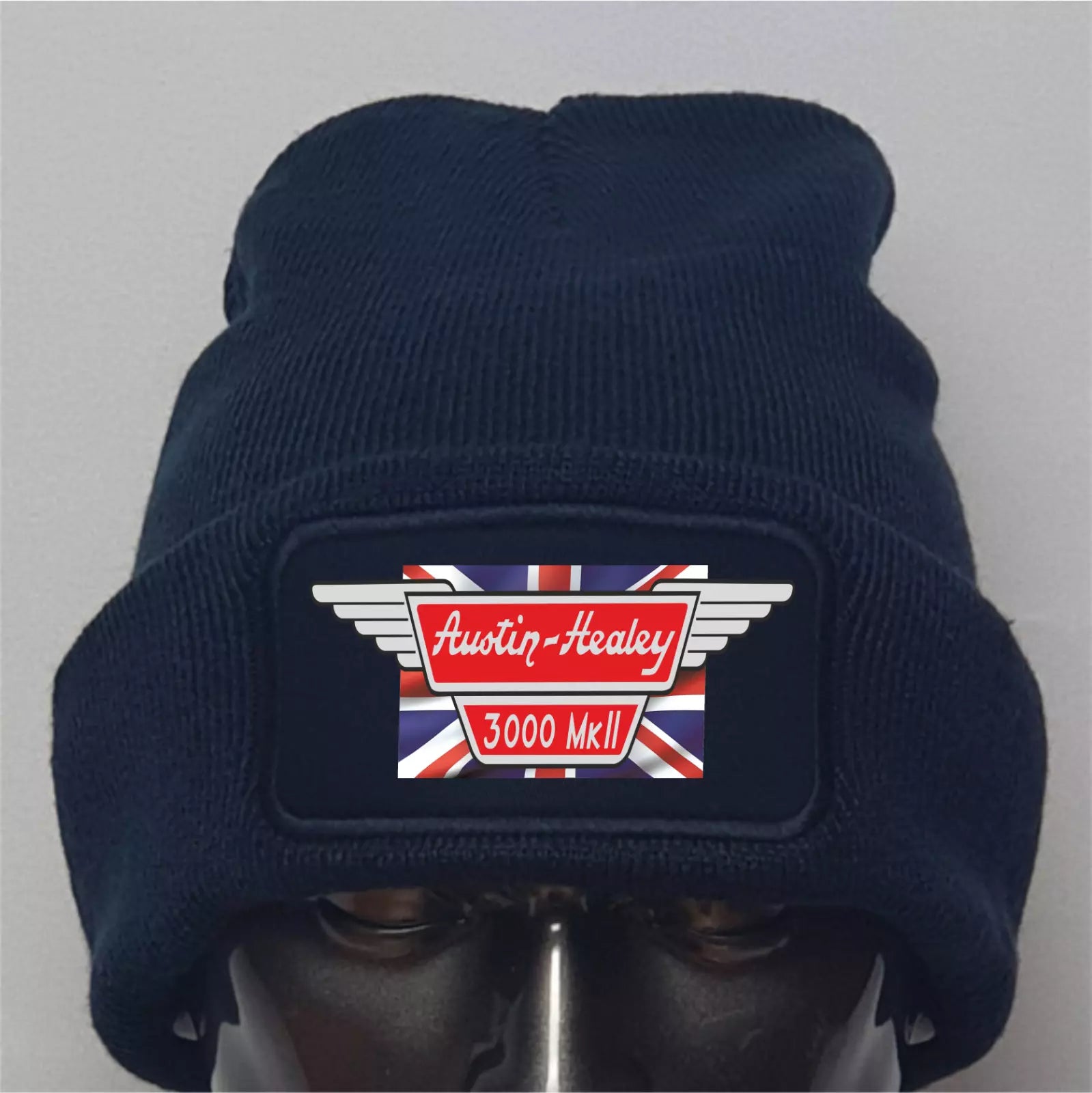 Navy blue beanie with Austin-Healey logo and Union Jack design on a gray background