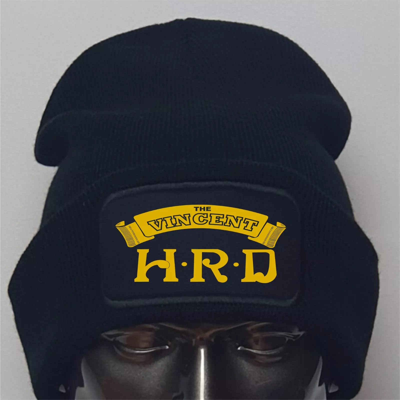 Black beanie with yellow text on a gray background