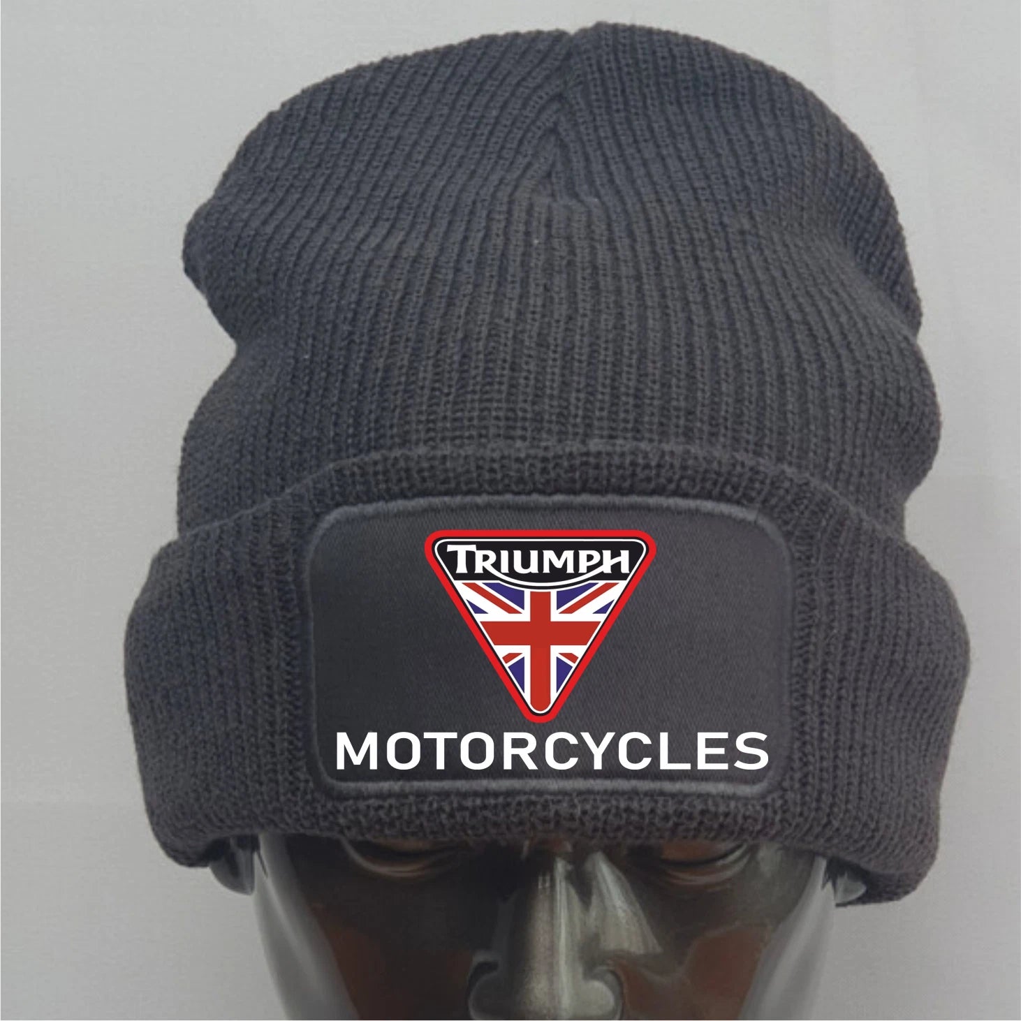 Dark gray knit beanie with Triumph Motorcycles logo on a mannequin head against a light gray background