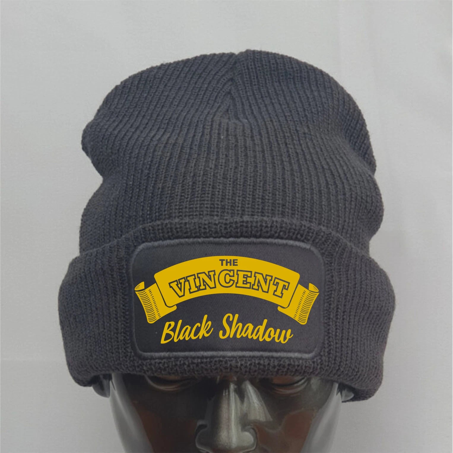 Gray knit beanie with yellow logo on a mannequin head against a gray background