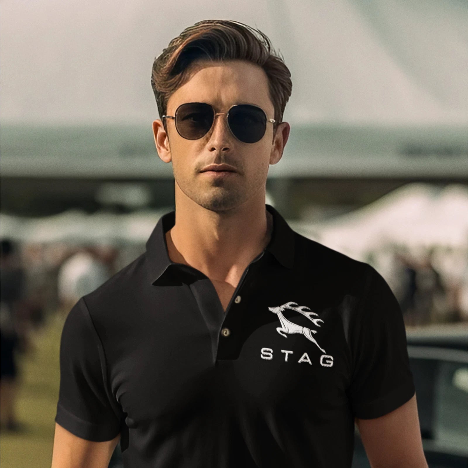 Man wearing a black polo shirt with a logo, standing outdoors.