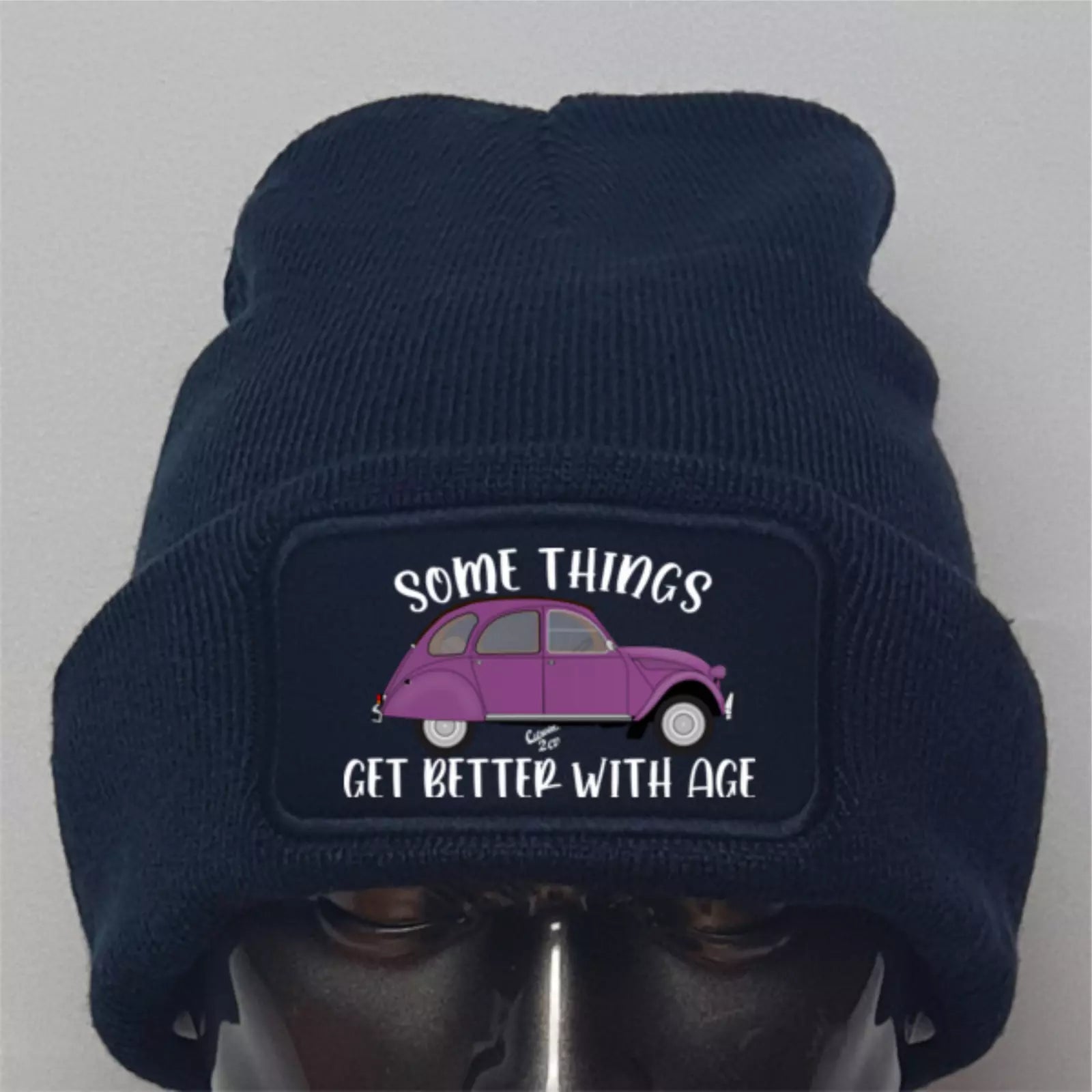 Navy blue beanie with a purple car graphic and text on a gray background