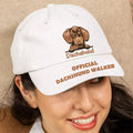 Person wearing a white cap with a dachshund design and text on a beige background