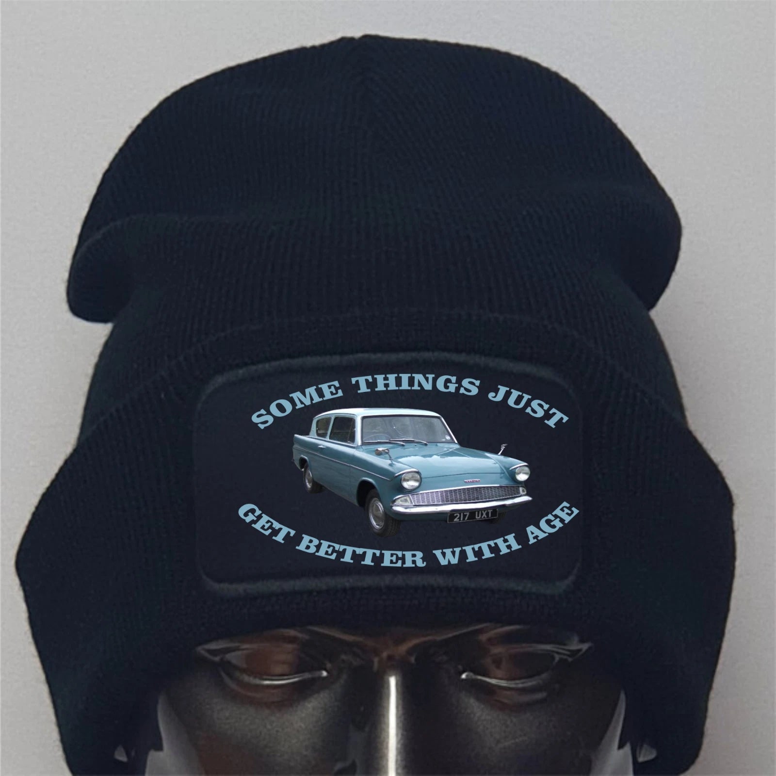 Black beanie with vintage car graphic and text on a mannequin head against a gray background
