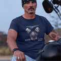 Man wearing a navy blue t-shirt with a motorcycle engine graphic, sitting on a motorcycle.