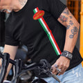 Person wearing a black t-shirt with Moto Guzzi logo and Italian flag design, standing next to a motorcycle.