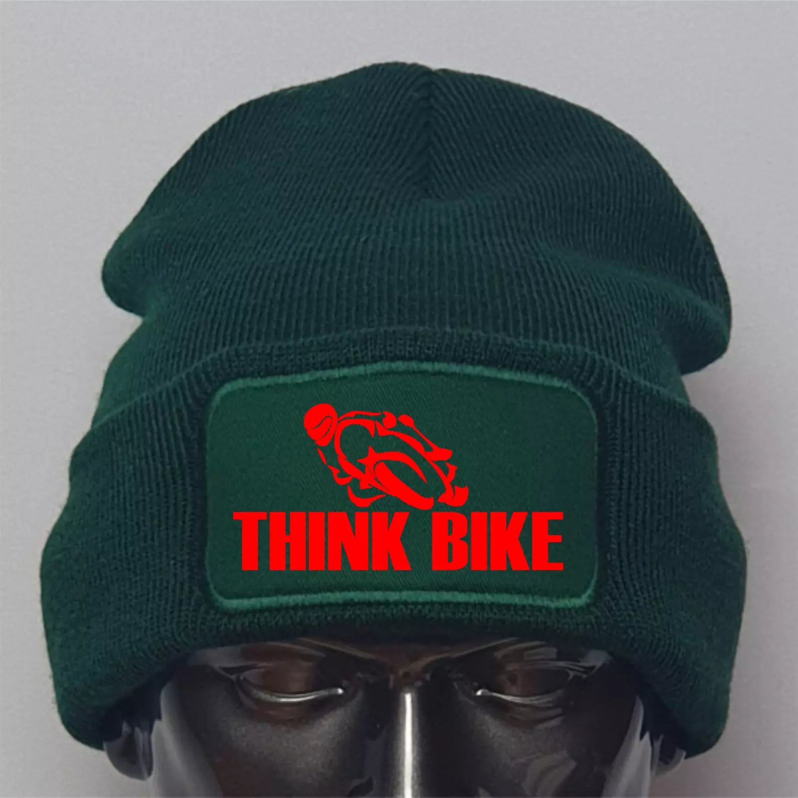 Green beanie with 'Think Bike' patch on a mannequin head against a gray background
