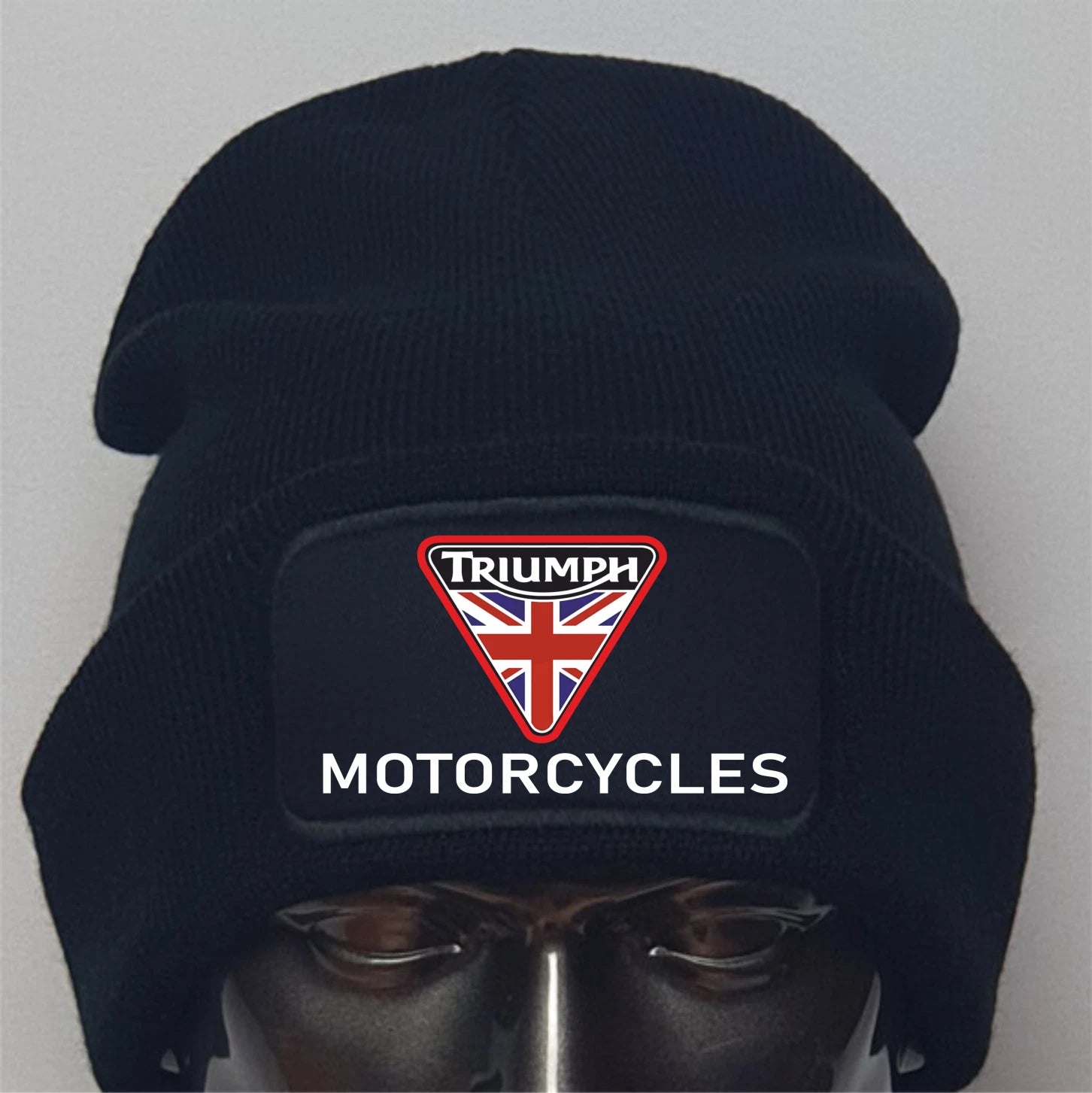 Black beanie with Triumph Motorcycles logo on a mannequin head against a gray background